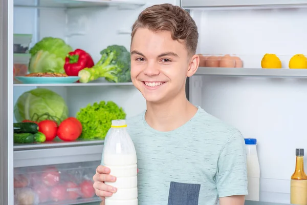 Мальчик с едой возле холодильника — стоковое фото