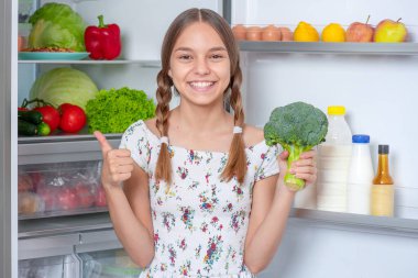 Buzdolabının yanında yemeği olan kız.