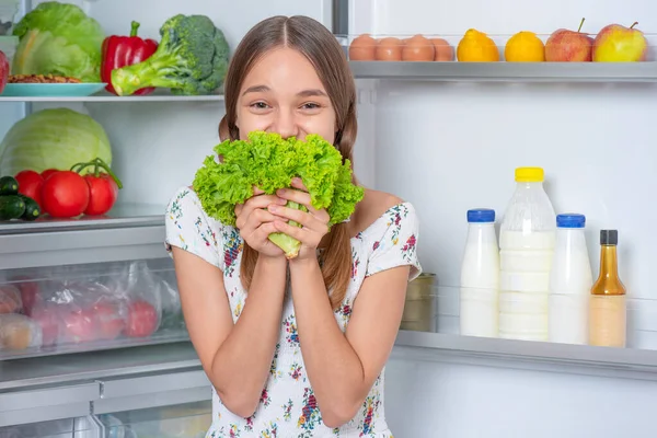 Menina com comida perto da geladeira — Fotografia de Stock