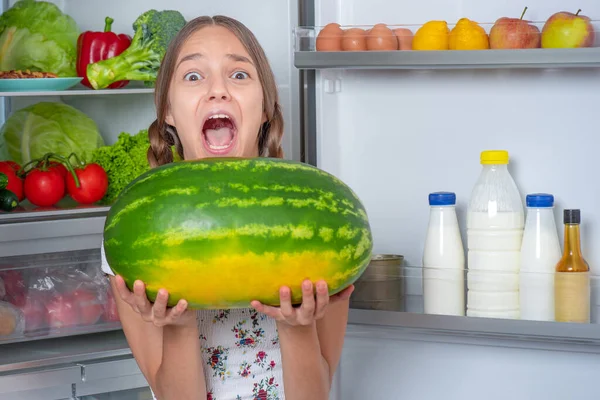 Menina com comida perto da geladeira — Fotografia de Stock