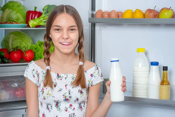 Chica con comida cerca de nevera — Foto de Stock