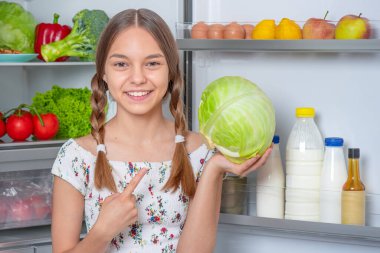Buzdolabının yanında yemeği olan kız.