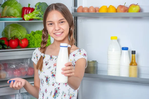 Menina com comida perto da geladeira — Fotografia de Stock