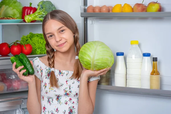 Flicka med mat nära kylskåp — Stockfoto