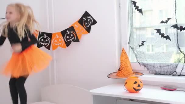 4k. Halloween kids. little blonde girl in witch costume having fun dancing at home, jumping on bed. Ready for the holiday — Stock Video