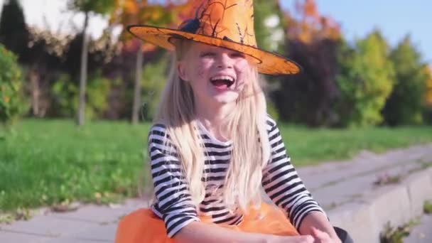 4k. Lachend gelukkig blond meisje in Halloween heksenkostuum op straat. Kind heeft plezier buiten — Stockvideo