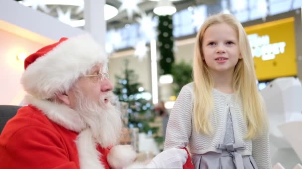 Санта-Клаус разговаривает и играет в сюрпризы с детьми в торговом центре. Рождественские продажи и пожелания — стоковое видео