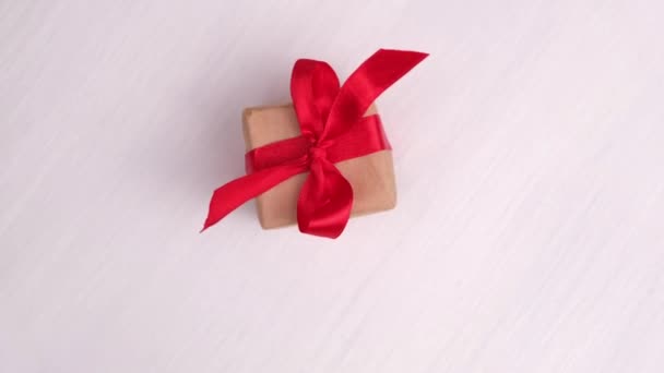 Confezione regalo con nastro rosso che gira su fondo in legno rosa. Rotazione a 360 gradi. loop senza soluzione di continuità. Concept vendita, prezzo scontato, vacanze di Natale e shopping. — Video Stock
