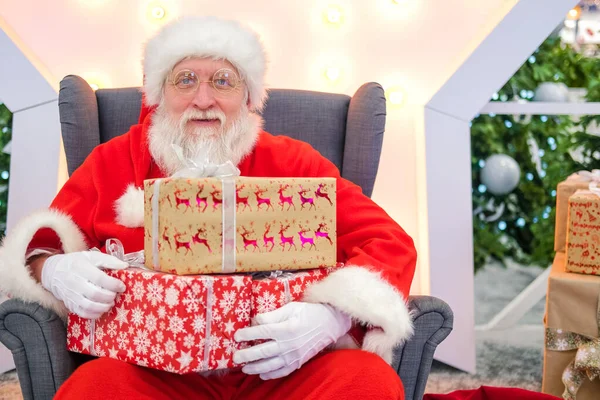 Gerçek otantik Noel Baba 'nın portresi elinde Noel hediyeleriyle alışveriş merkezinde oturuyor.. — Stok fotoğraf