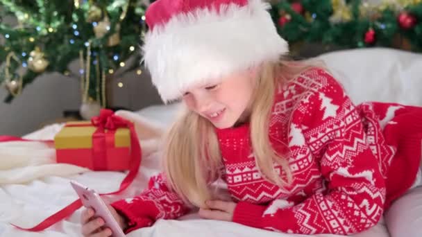 4k Weihnachten online Glückwunsch. Lächelndes Mädchen mit Handy für Videoanrufe. Kind redet mit Freunden und Eltern — Stockvideo