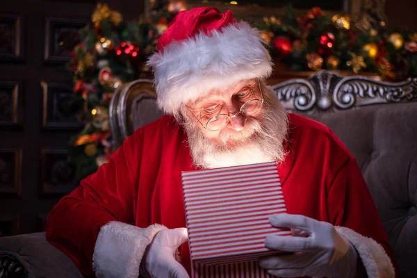 Der Weihnachtsmann eröffnet das Weihnachtsgeschenk. Erfüllung von Wünschen. Weihnachtsmann sitzt zu Hause am Weihnachtsbaum — Stockfoto