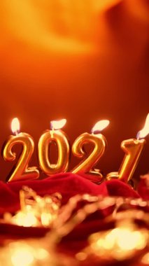 Mutlu yıllar 2021 kutlamaları. Noel arkaplanında 2021 numara şeklinde altın yanan mumlar. Dikey video