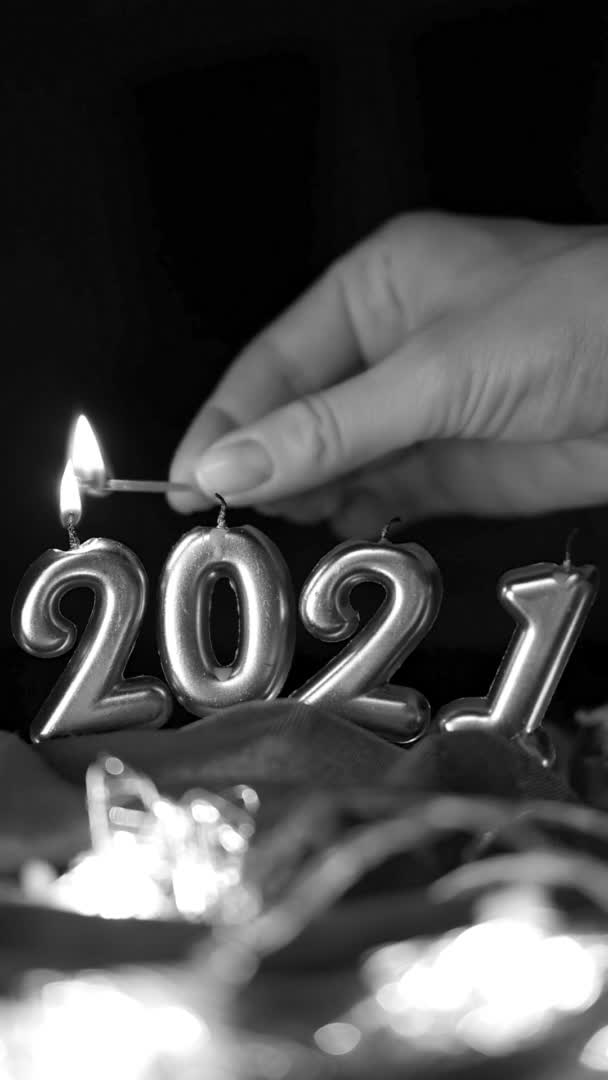Ruční zapalování svíček v podobě2021. Vertikální černobílé video. Zlaté hořící svíčky na tmavém pozadí. Šťastný Nový rok 2021 oslava. — Stock video
