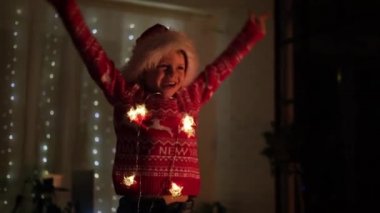 Evde Noel Baba şapkasıyla dans eden heyecanlı Noel çocuğu. Yeni yıl ve tatiller. Noel mutluluğu. Çocuk eğleniyor.
