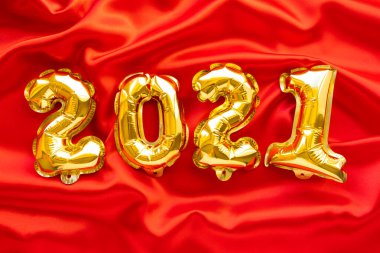 Folyo balonları 2021 numaralı formda. Yeni yıl kutlaması. Kırmızı şenlikli arka planda altın hava balonları. Tatil partisi dekorasyonu. en üstteki görünüm.