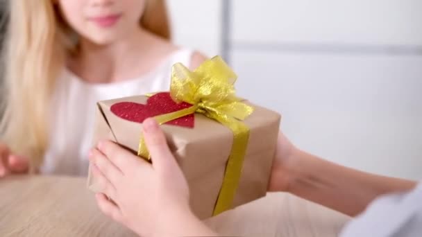 Kleiner Junge schenkt seinem geliebten Mädchen eine Geschenkbox zum Valentinstag. Glücklich lächelnde blonde Kinder feiern den Valentinstag. Zeitlupe. — Stockvideo