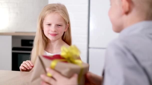 小さな男の子は彼の最愛の女の子バレンタインデーギフトボックスを与えます。バレンタインデーを祝う幸せな笑顔のブロンドの子供たち。スローモーション. — ストック動画