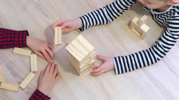 4k crianças jogando jogo de torre de remoção de bloco de madeira em casa. Menina loira e menino se divertindo juntos - Jogo de tabuleiro e conceito de lazer para crianças — Vídeo de Stock