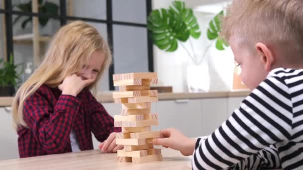 4k children playing wooden block removal tower game at home. Blonde girl and boy having fun together - Board game and kids leisure concept — Stock Video