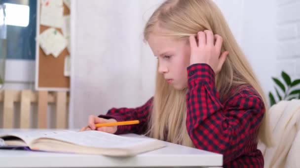 4k Colegiala rubia estudiando en casa haciendo la tarea de la escuela. Libros de entrenamiento y cuadernos en la mesa. Educación a distancia en línea. — Vídeos de Stock
