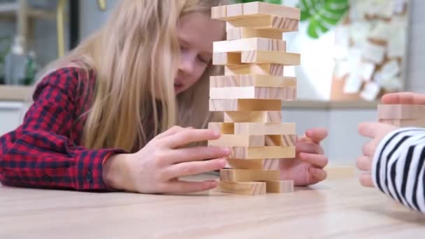 自宅で木製ブロック除去タワーゲームをプレイ4kの子供たち。一緒に楽しんでいるブロンドの女の子と男の子-ボードゲームと子供のレジャーコンセプト — ストック動画