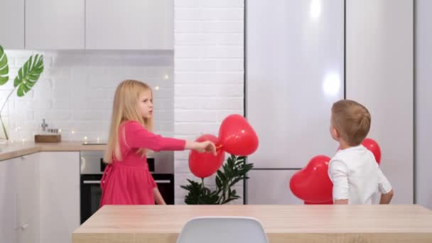 Menino e menina dançando com balões em forma de coração vermelho em casa. A celebrar o Dia dos Namorados. Movimento lento. — Vídeo de Stock