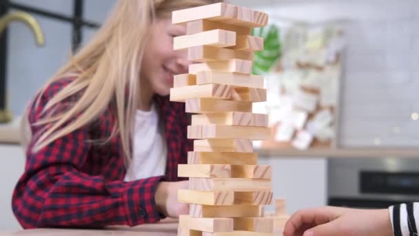 4k crianças jogando jogo de torre de remoção de bloco de madeira em casa. Menina loira e menino se divertindo juntos - Jogo de tabuleiro e conceito de lazer para crianças — Vídeo de Stock