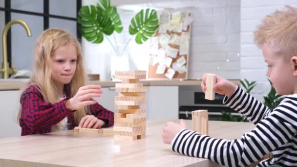 4k kinderen spelen houten blok verwijdering toren spel thuis. Blond meisje en jongen hebben plezier samen - bordspel en kinderen vrijetijdsconcept — Stockvideo