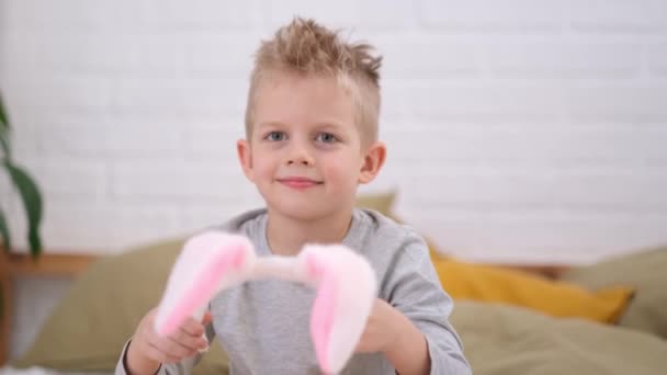 Portret wielkanocnego dziecka. Chłopiec zakładający królicze uszy na głowę i bawiący się w domu. Wesoły uśmiech dziecka. — Wideo stockowe