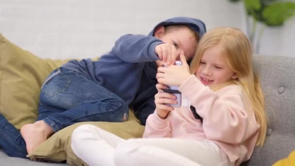 Kinderen broer en zus op zoek naar smartphone scherm thuis. Kleine jongen en meisje spelen online games op mobiele telefoon. — Stockvideo