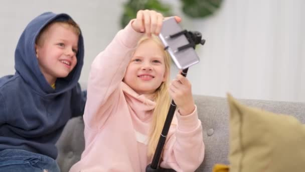 Kinderen bloggers praten met volgers, live streaming op zoek naar smartphone scherm thuis. Kleine jongen en meisje maken selfie. — Stockvideo