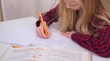 4k Sarışın liseli kız evde ders çalışıyor. Ödev yapıyor. Eğitim kitapları ve defterler masanın üstünde. Uzaklık öğrenimi çevrimiçi eğitim.
