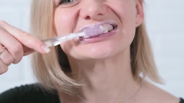 Diş fırçalı genç bayana yakın gülümse. Orta yaşlı bir kadın beyaz tuğlalı arka planda dişlerini fırçalıyor. Sağlık, diş sağlığı... — Stok video