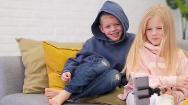 Kinderen bloggers praten met volgers, live streaming op zoek naar smartphone scherm thuis. Kleine jongen en meisje maken selfie. — Stockvideo