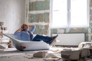 Yenileme dairesi. Yaratıcı hikaye genç mutlu kadın odanın ortasında küvette oturuyor. Boş duvarlar, kendi elleriyle tamir ettikleri ev.