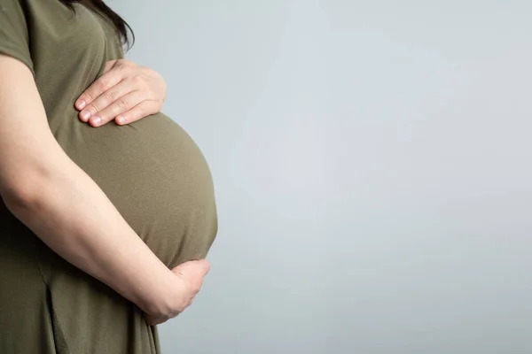 Здорова вагітність. Вид збоку вагітна жінка з великим черевом підвищена вагітність в руках. Банерна копія тексту — стокове фото