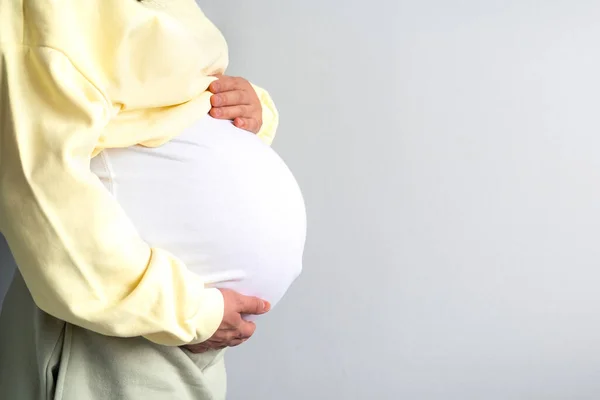 Здорова вагітність. Вид збоку вагітна жінка з великим черевом підвищена вагітність в руках. Банерна копія тексту. Модний колір, що освітлює жовті фіолетові кінцеві сірі . — стокове фото