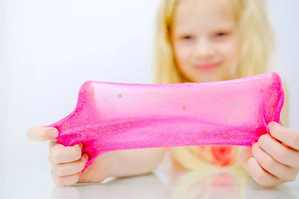 金发姑娘把粉色闪光的黏液伸向两边.孩子们用手玩黏糊糊的玩具.做黏液。复制空间。有选择的重点. — 图库照片