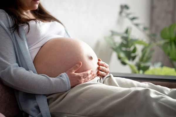Mujer embarazada con el vientre grande embarazo avanzado descansando sentado en el sofá en casa.Embarazo saludable y feliz moterinty — Foto de Stock
