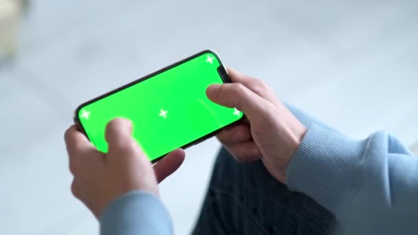 4k. hombre jugando juego usando iPhone 12 smartphone visualización de pantalla verde en el teléfono horizontal prensa dedo croma clave en línea de cerca en dos manos en casa 24.04.21 San Petersburgo Rusia — Vídeos de Stock