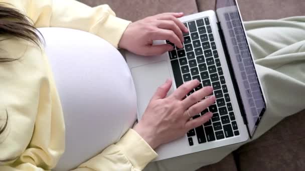 4k Top view Verwachte moeder die op afstand online werkt vanuit huis. close-up zwanger jong vrouw handen op laptop met Groot buik geavanceerde zwangerschap — Stockvideo