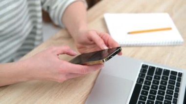 4 bin. iPhone 12 'yi kullanan akıllı telefon tuşlarına basan, sosyal medyada yazı yazan ya da internetten alışveriş yapan bir kız. Cep telefonu iki elinle evde ya da işte. Masa 24.04.21 St. Petersburg Rusya 'daki bilgisayar.