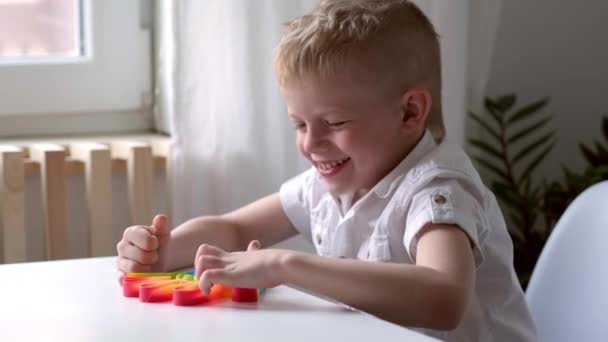 Criança brincar com pop-lo brinquedo sensorial. Menino pressiona em colorido arco-íris squishy bolhas de silicone macio. Alívio de estresse e ansiedade. Jogo de alternância na moda para crianças e adultos estressados. — Vídeo de Stock