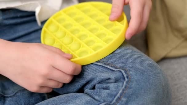 Jeu d'enfant avec pop it jouet sensoriel. Boy presse sur les bulles de silicone doux squishy jaune coloré. Soulagement du stress et de l'anxiété. Jeu de fidgeting tendance pour les enfants et les adultes stressés. — Video