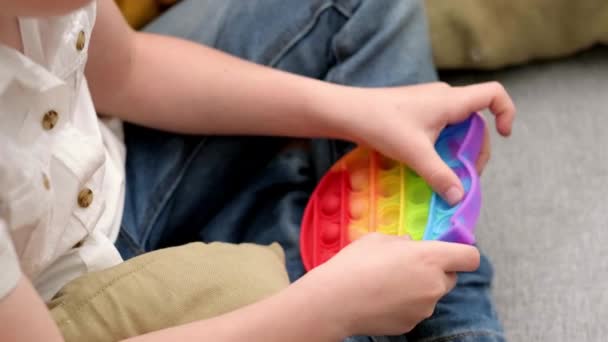 Jeu d'enfant avec pop it jouet sensoriel. Boy presse sur les bulles de silicone doux squishy arc-en-ciel coloré. Soulagement du stress et de l'anxiété. Jeu de fidgeting tendance pour les enfants et les adultes stressés. — Video