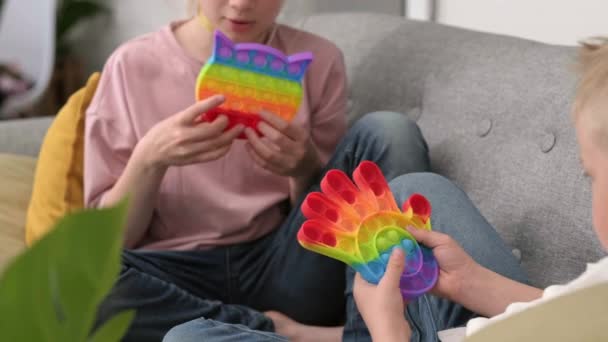 子供たちはそれを感覚おもちゃで遊んでいます。カラフルな虹色のずさんな柔らかいシリコーン泡を押す男の子と女の子。ストレスと不安緩和。トレンドフィギュアゲーム. — ストック動画