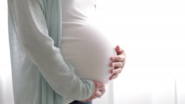 4k怀孕的孕妇爱抚她的肚子。女人的手碰她的肚子，等待孩子。分娩前的准备工作，女孩大肚子早产. — 图库视频影像
