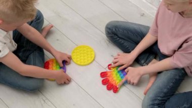Çocuklar duyusal oyuncakla oynuyorlar. Oğlan ve kız renkli gökkuşağı yumuşak silikon kabarcıklarına bastırıyor. Stres ve endişe giderici. Kıpır kıpır bir oyun. Üst görünüm.
