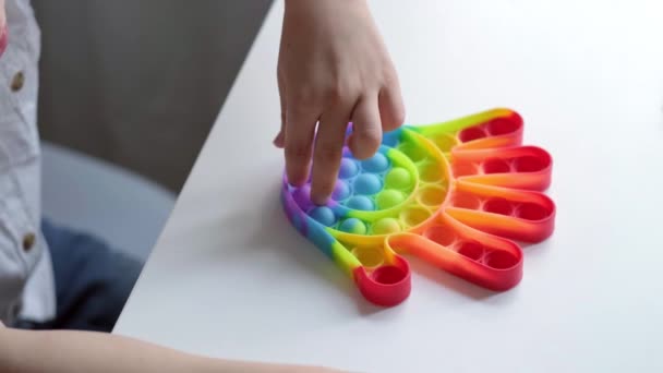 Jeu d'enfant avec pop it jouet sensoriel. Boy presse sur les bulles de silicone doux squishy arc-en-ciel coloré. Soulagement du stress et de l'anxiété. Jeu de fidgeting tendance pour les enfants et les adultes stressés. — Video