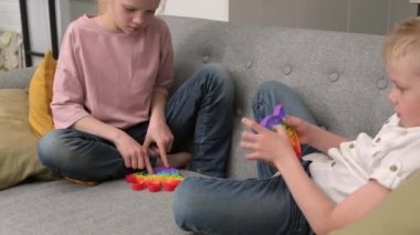 Çocuklar duyusal oyuncakla oynuyorlar. Oğlan ve kız renkli gökkuşağı yumuşak silikon kabarcıklarına bastırıyor. Stres ve endişe giderici. Kıpır kıpır etme oyunu.